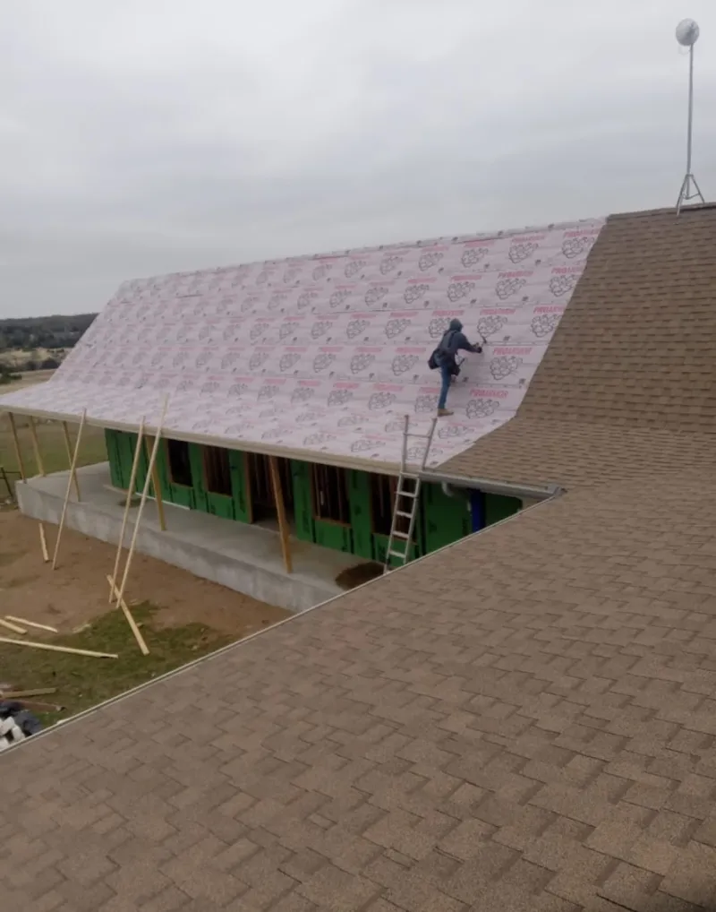 Worker preparing underlayment for a metal roof installation in Country Walk